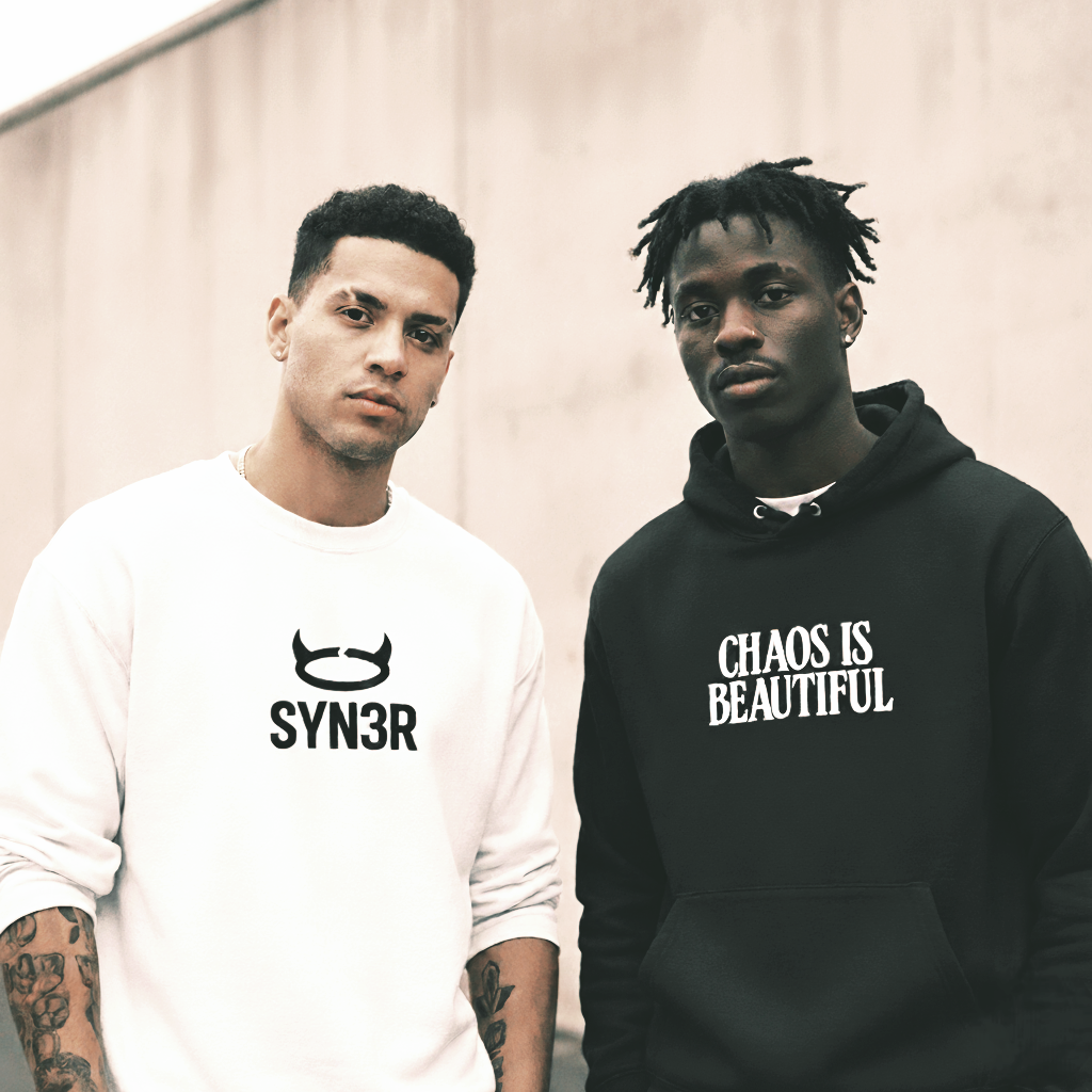 Two men wearing SYN3R streetwear hoodies and sweatshirts with bold minimalist designs outdoors
